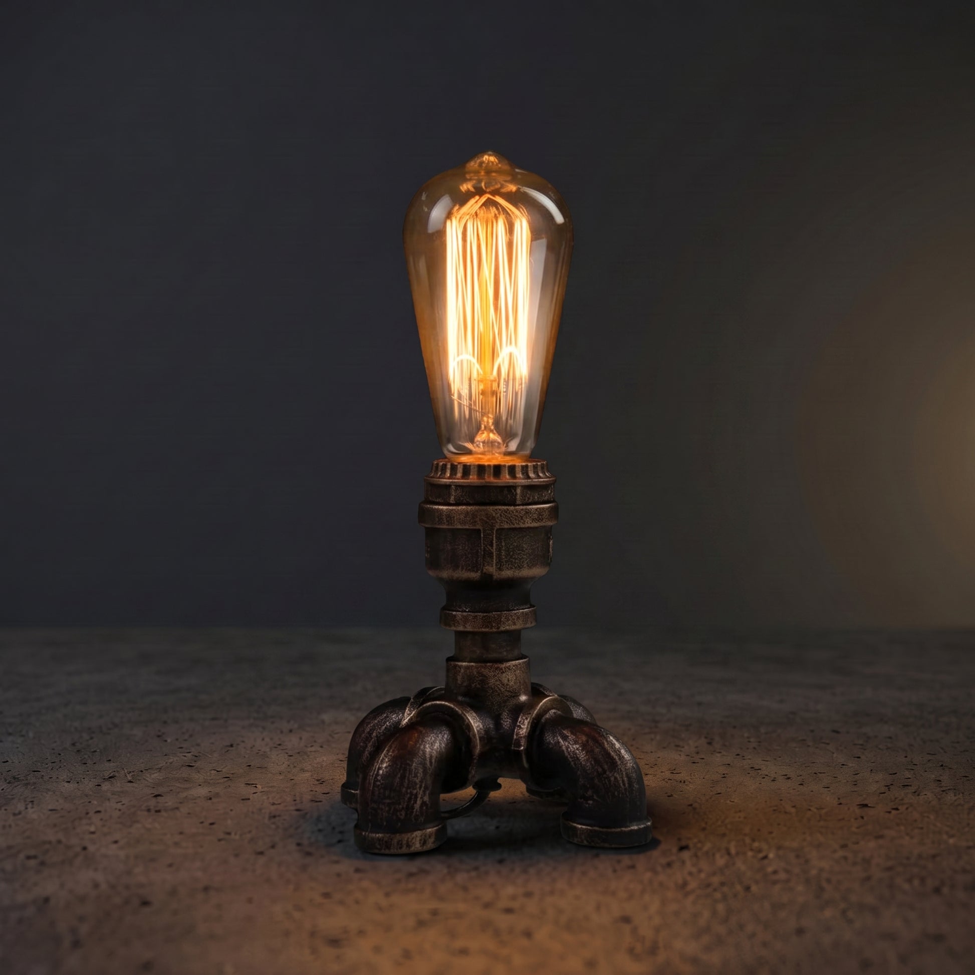 Industrial pipe desk lamp on a dark wooden desk with Edison bulb glowing warm