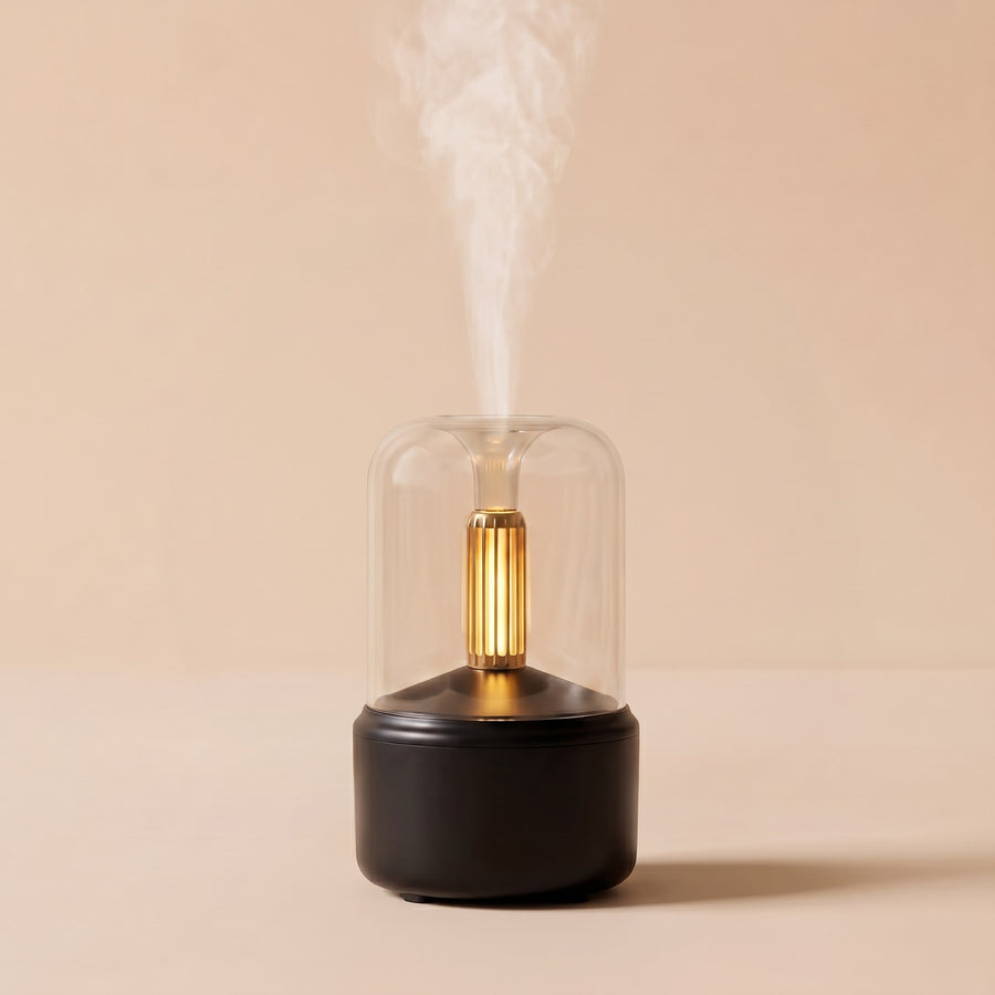 Candlelight Diffuser in black, its glass dome lit by a warm amber light and mist rising from the top