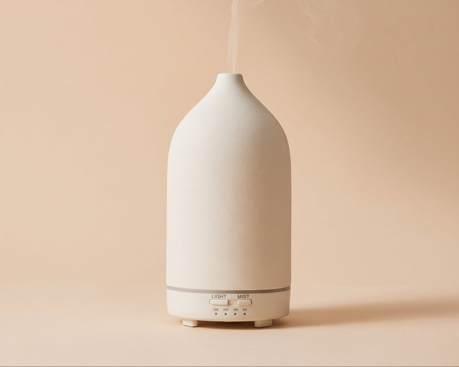 Matte Ceramic Diffuser in white with mist rising, on a sand backdrop