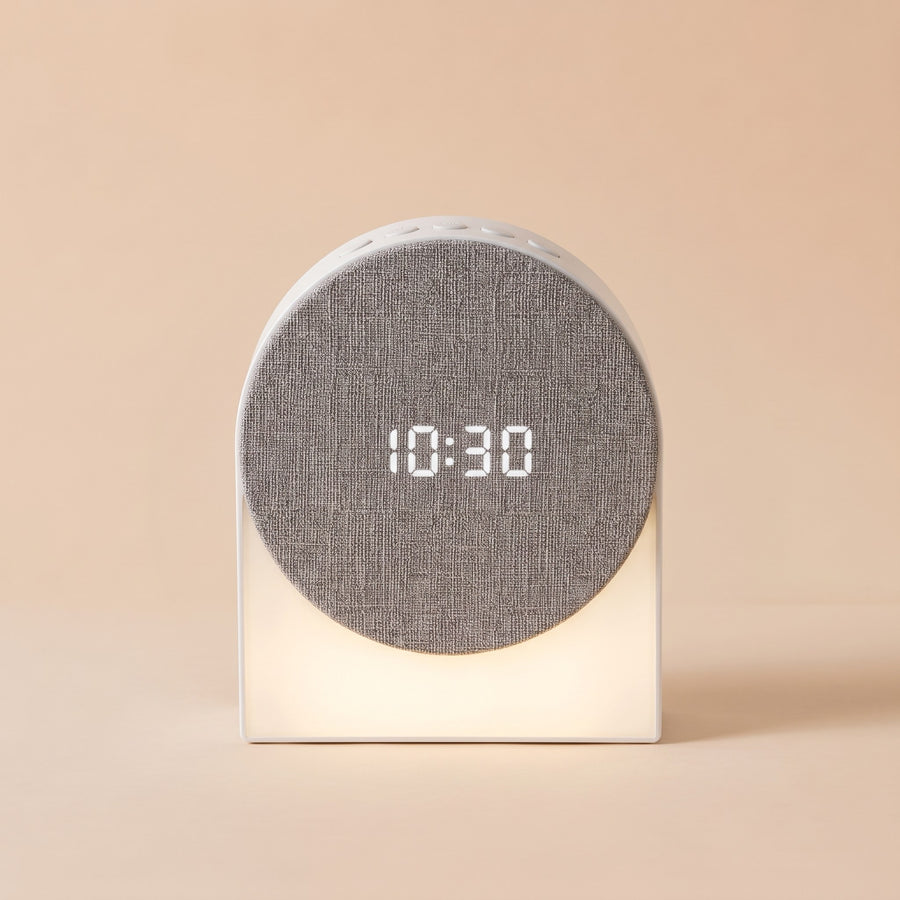 Round Sound Clock in white, fabric speaker face showing 10:30 and a soft light below